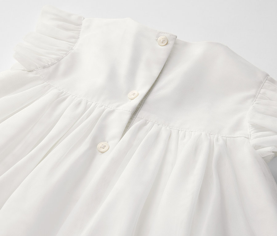 Detailansicht eines Baby-Tüllkleids mit Knöpfen am Rücken.