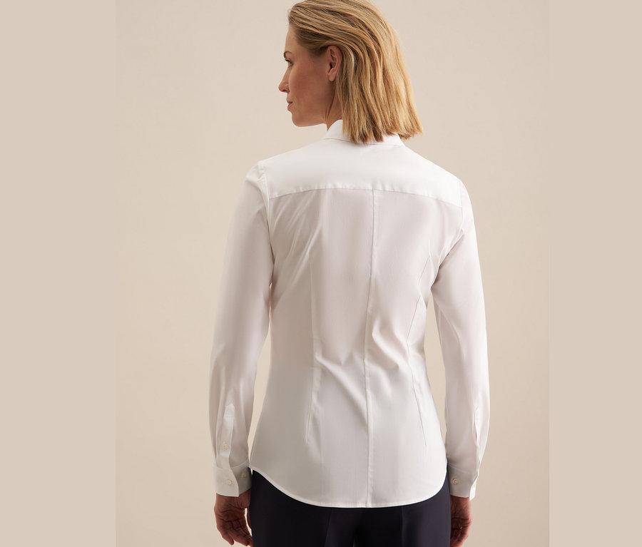 Rückansicht einer blonden Frau, die eine weiße Seidensticker Slimfit Bluse trägt.