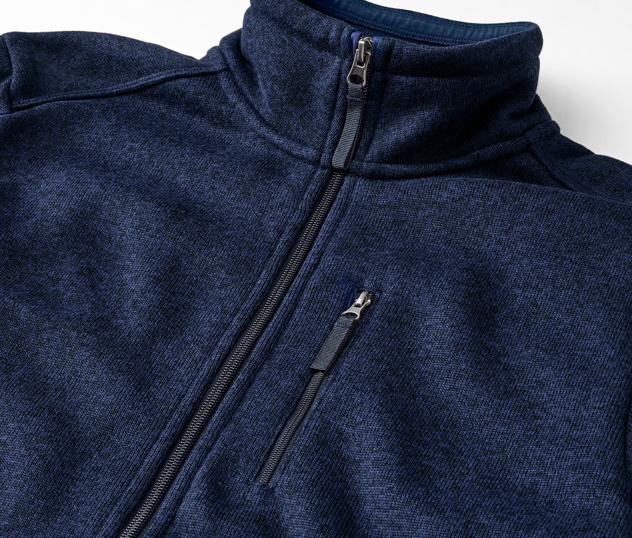 Detailaufnahme einer marineblauen Strickfleece-Jacke mit Reißverschluss.