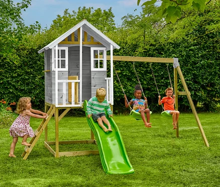 Vier Kinder spielen im Garten auf dem Stelzenhaus »Valli« mit Rutsche und Doppelschaukel.