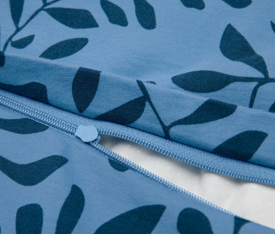 Detailansicht eines blauen Bettbezugs mit Reißverschluss und Blattmuster.