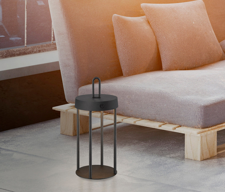 Eine schwarze JUST LIGHT LED-Akku-Tischleuchte »Anselm« steht neben einem Sofa.