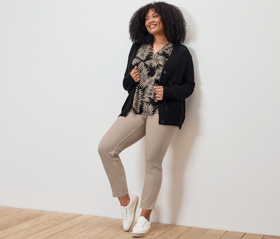 Frau posiert in 7/8-Treggings, Oberteil und Strickjacke.