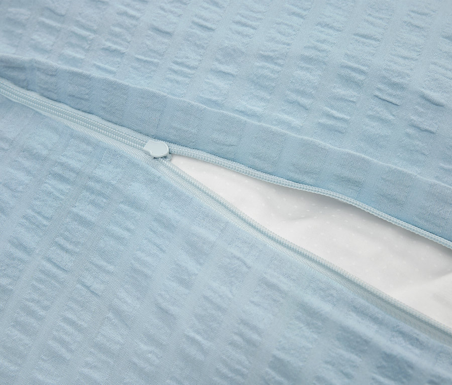 Detailaufnahme eines hellblauen Kissenbezugs mit Reißverschluss und weißer Innenseite.
