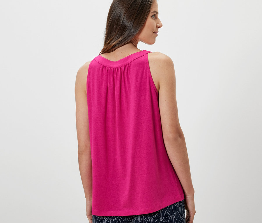 Frau schaut über die Schulter und trägt ein pinkes Top.