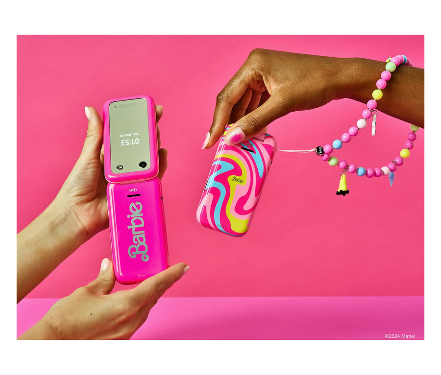 Eine Frau hält ein rosa HMD Barbie Phone 4G und eine Hülle mit einem Perlenarmband vor einer rosa Wand.