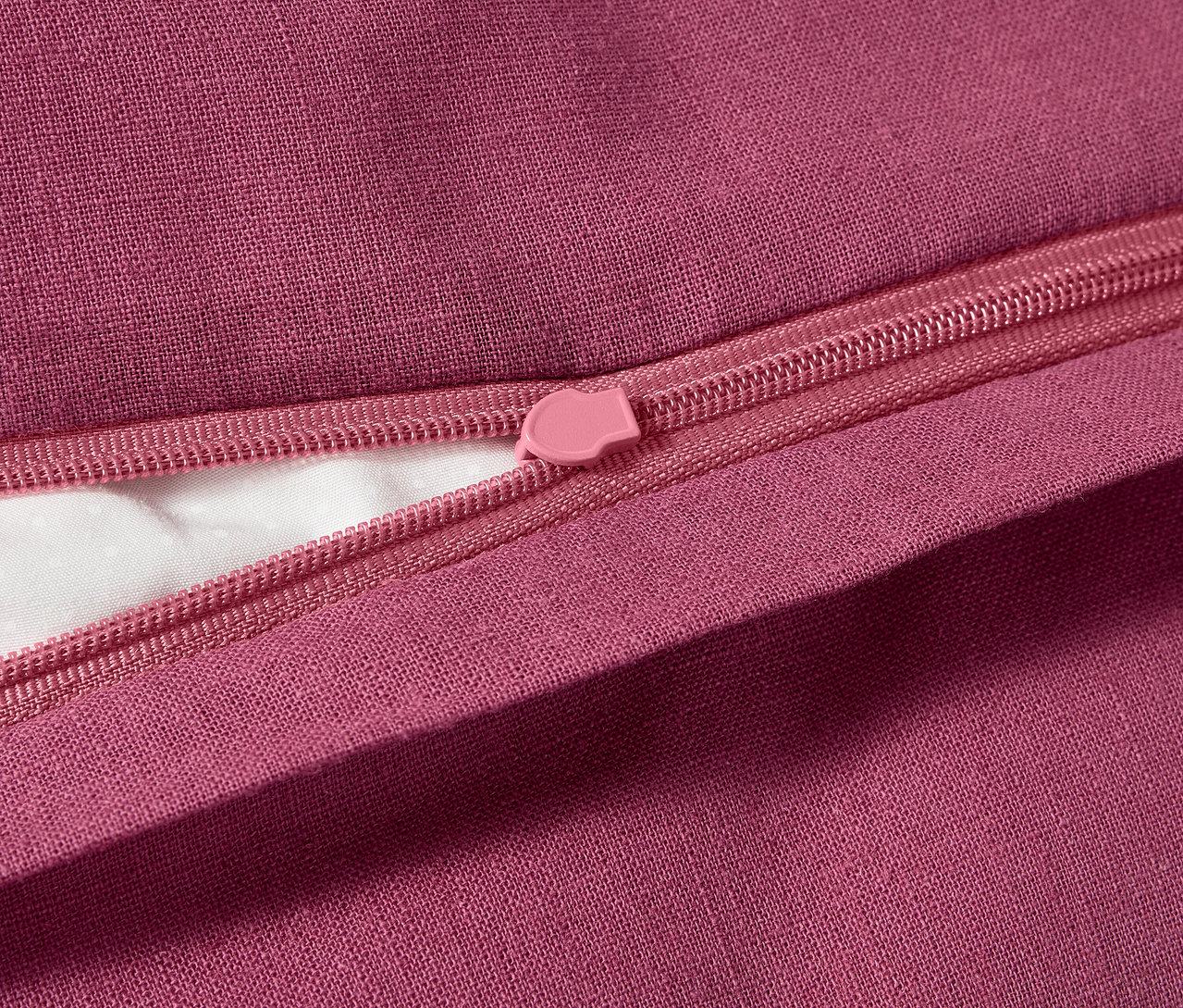 Detailaufnahme von Halbleinen-Bettwäsche in Übergröße mit rosafarbenem Reißverschluss.
