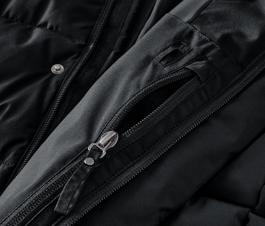 Detailaufnahme einer schwarzen Jacke mit geöffnetem Reißverschluss an der Tasche.