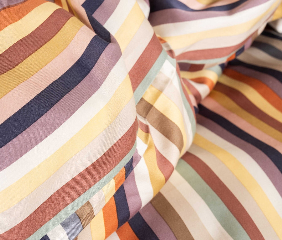 Nahaufnahme von gerafftem Stoff mit bunten Streifen in Orange, Gelb, Braun, Lila und Blau.