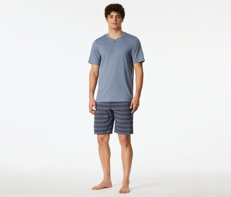Mann im blauen Pyjama-Oberteil mit Knopfleiste und gestreiften Shorts.