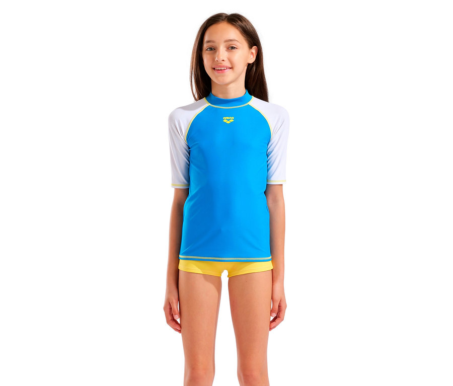 Mädchen trägt ein blaues Arena-Schwimmshirt mit weißen Ärmeln und gelbe Badehose.