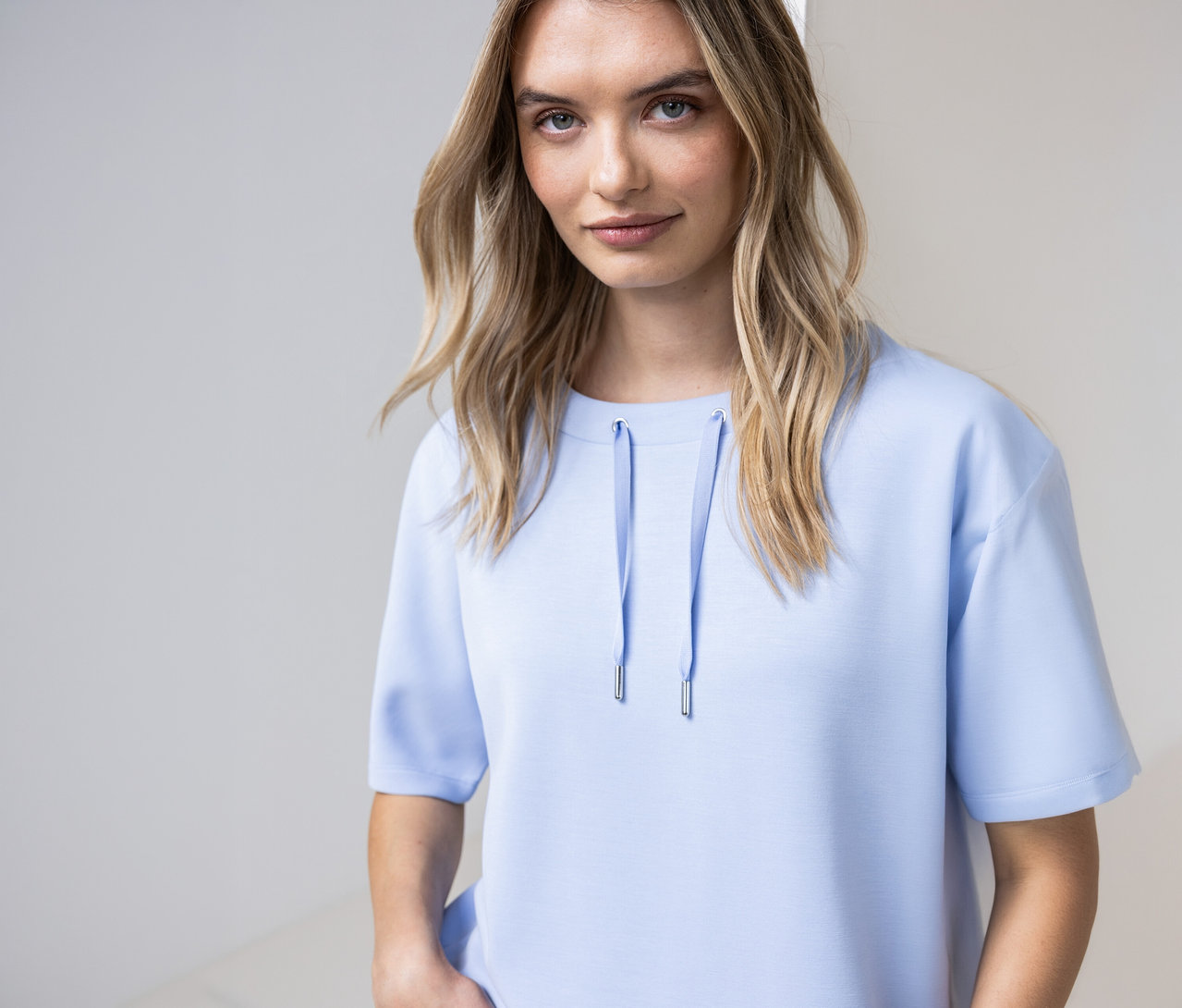 Frau trägt ein hellblaues Street One Shirt mit Kordeln am Ausschnitt.