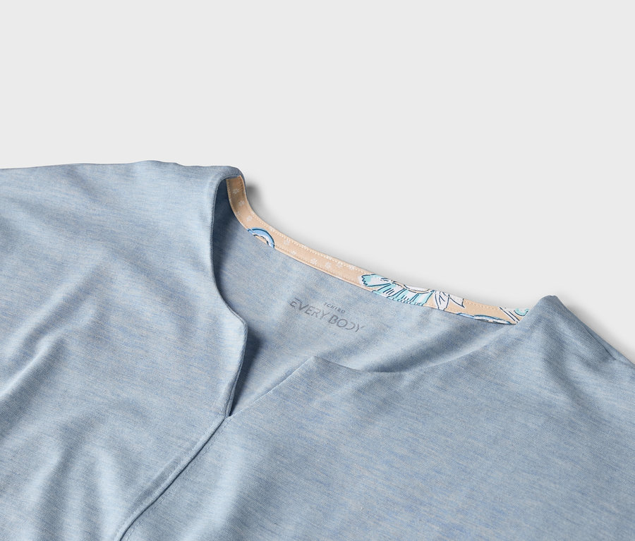Nahaufnahme eines hellblauen "EVERY BODY" T-Shirts mit V-Ausschnitt und floralem Kragen.