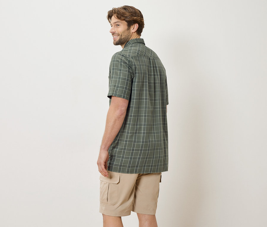 Mann von hinten, trägt ein kariertes, kurzärmeliges Hemd und beigefarbene Shorts.