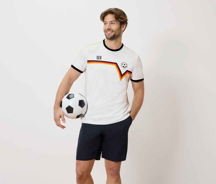 Mann mit Deutschland Trikot hält einen Fußball in der Hand.