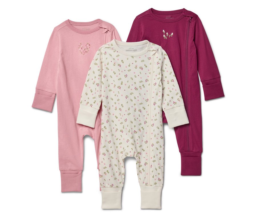 Drei Baby-Schlafanzüge in Rosa, Weiß mit Blumenmuster und Lila liegen übereinander.