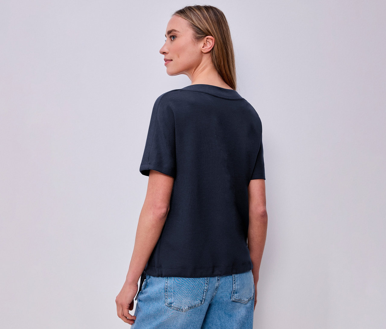 Frau von hinten mit marineblauem Street One Kurzarmshirt und Jeans.