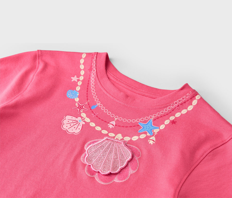 Nahaufnahme eines rosafarbenen T-Shirts mit aufgedruckter Halskette mit Muscheln und Seesternen.