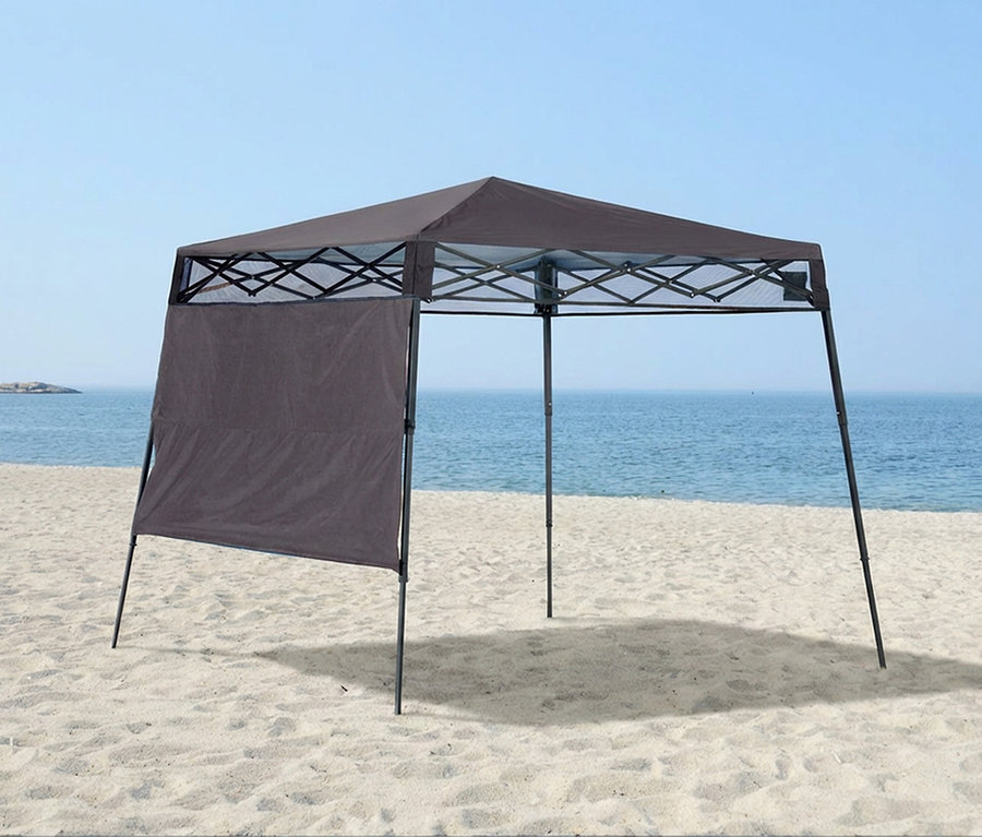 Braunes Faltzelt mit einer Seitenwand steht am Strand vor dem Meer.