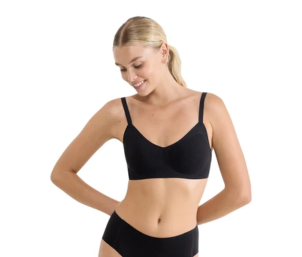 Lächelnde Frau trägt einen schwarzen, gerippten sloggi ZERO Feel Pure Soft BH und passende schwarze Slips.