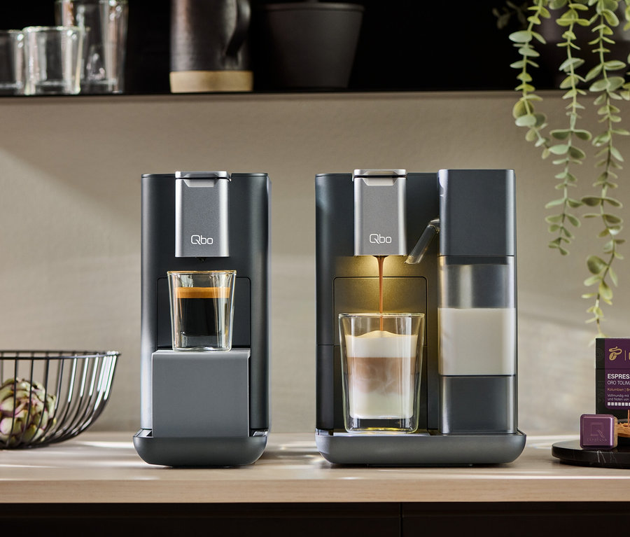Zwei Qbo MILK MASTER Kaffeemaschinen, eine bereitet Espresso zu, die andere Latte Macchiato.