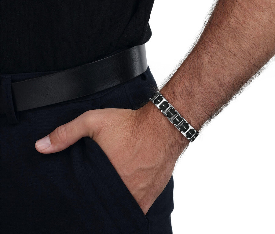 Nahaufnahme eines Mannes mit einem silberfarbenen Panzerarmband, dessen Hand in der Hosentasche steckt.