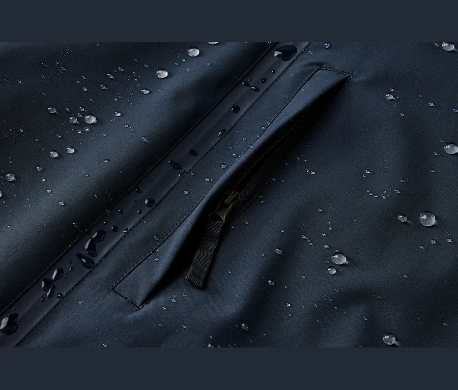 Dunkelblauer, wasserabweisender Stoff mit Wassertropfen und einer Reißverschlusstasche.