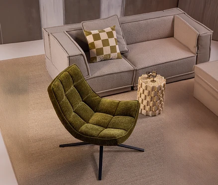 Grüner, gesteppter WOOOD Drehsessel »Maudi« vor einer hellgrauen modularen Couch mit kariertem Kissen und beigem Beistelltisch mit Gläsern.
