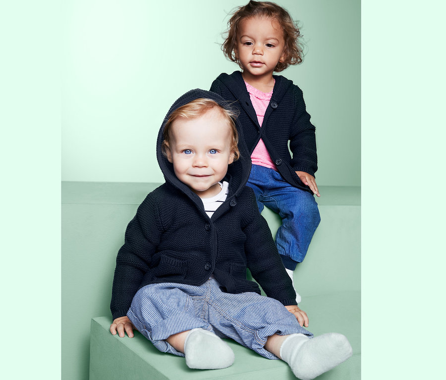 Kinder sitzen auf Stufen und tragen Strickjacken.