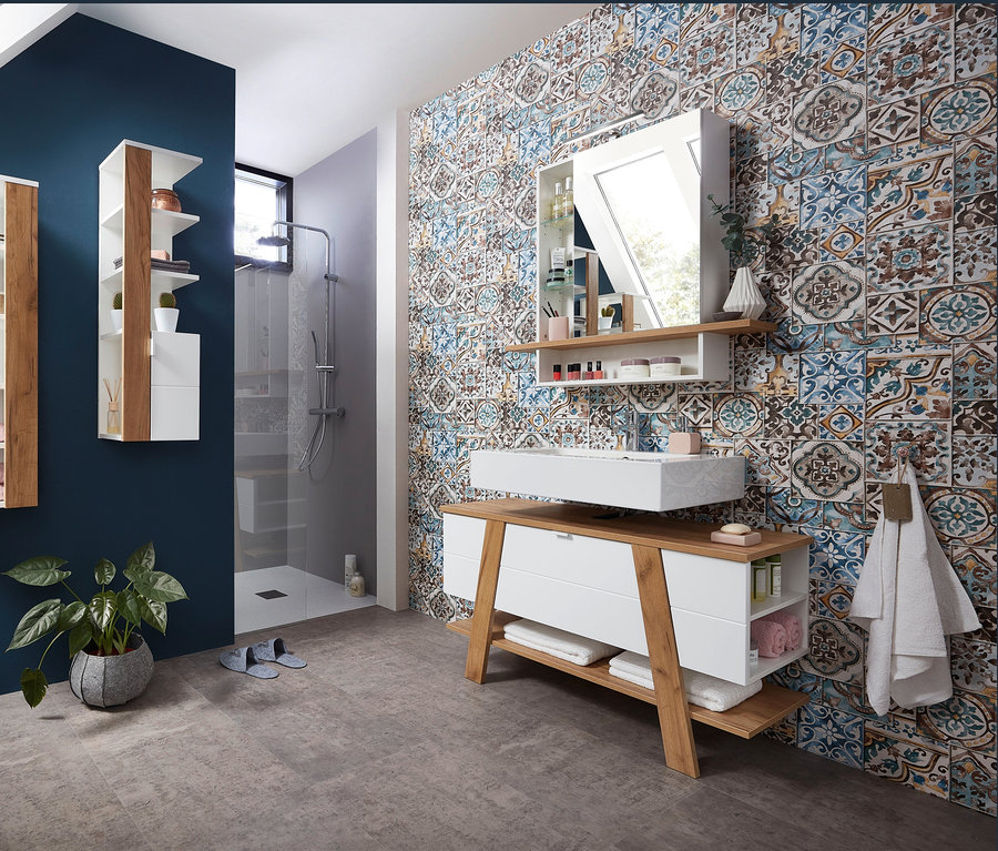 Badezimmer mit Novolino Waschbecken-Unterschrank und Novolino Spiegelschrank vor blau gemusterter Wand.