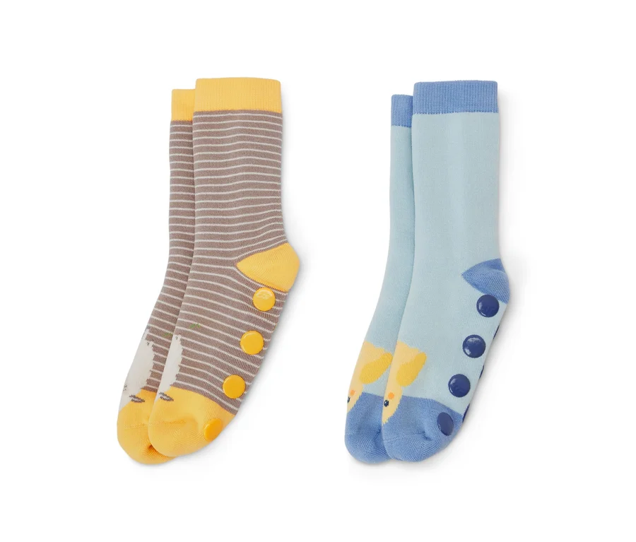 Zwei Paar Kinder-Antirutsch-Socken. Ein Paar ist braun-weiß gestreift mit gelben Akzenten und Vogelbild, das andere Paar ist hellblau mit Giraffenbild und dunkelblauen Punkten.