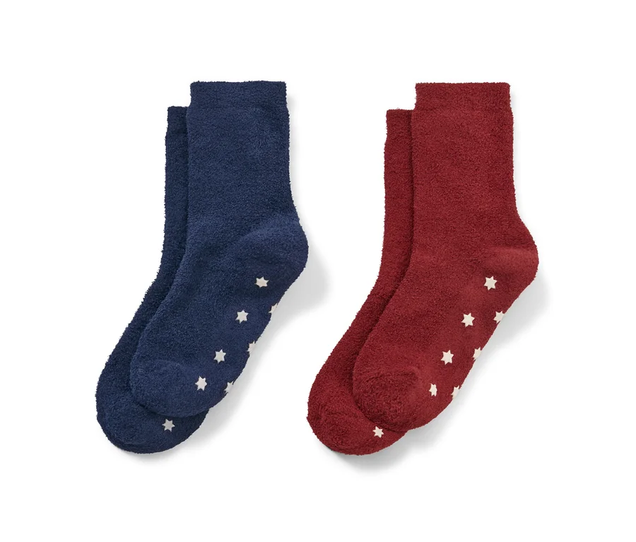 Zwei Paar Kinder-Kuschelsocken: ein Paar dunkelblau, ein Paar rot, jeweils mit weißen Sternen.