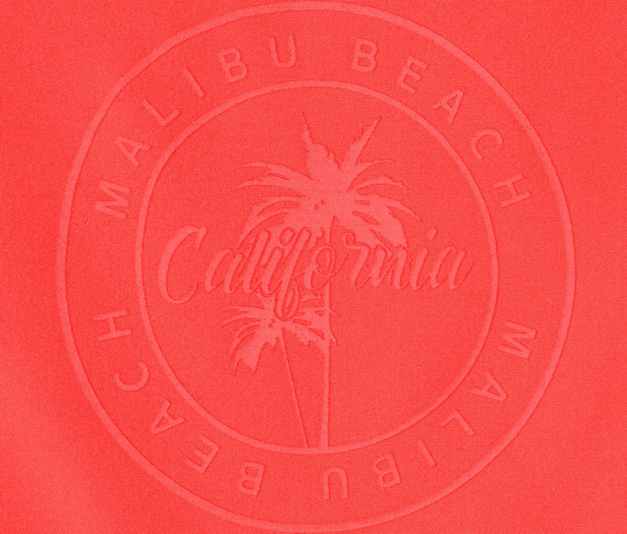 Detailaufnahme der roten Boardshorts mit Malibu Beach California Logo.