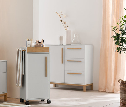 Hellgraues Badezimmer mit Eklund Bad-Hochschrank, Waschbeckenunterschrank mit Schubladen und Beistellschrank. Dazu beige-weiß gestreifte Handtücher, Duschvorleger und Aufbewahrungskörbe.