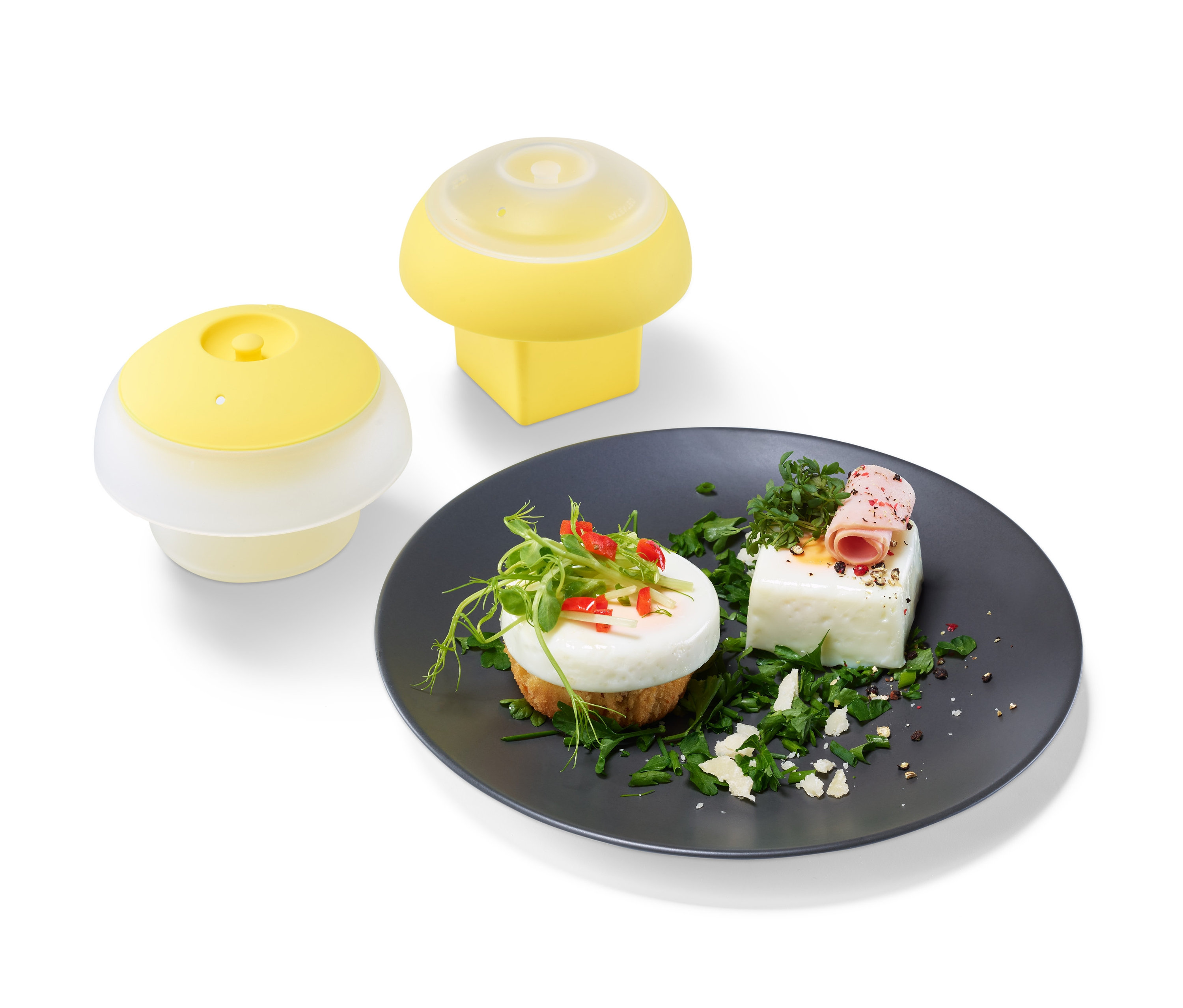 Zwei gelbe Eierformer-Sets und ein Teller mit mit Grünzeug verzierten Eiern.