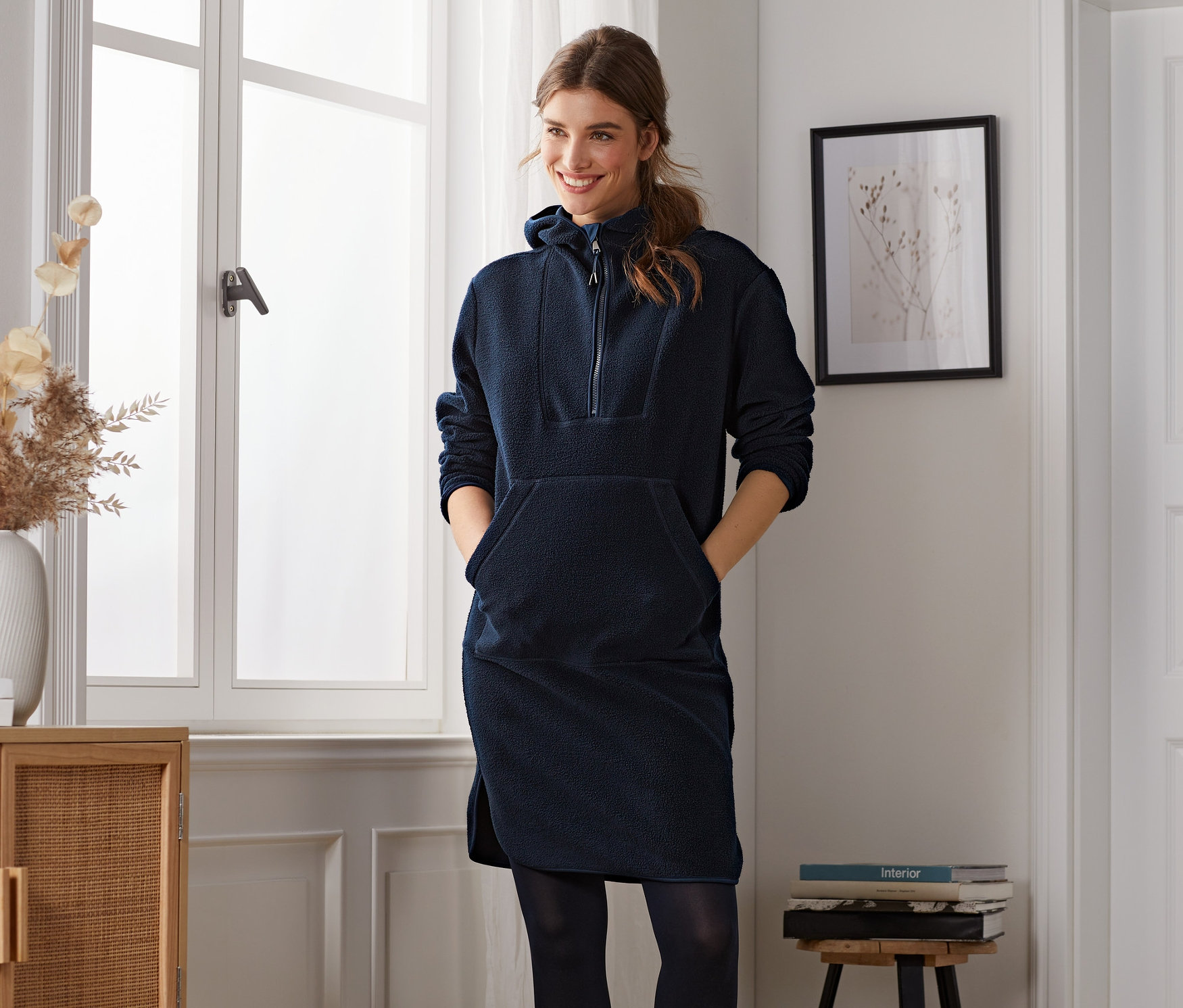 Eine lächelnde Frau posiert in einem blauen Fleecekleid.