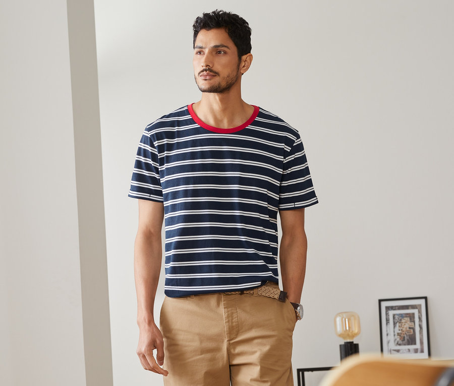 Mann trägt ein T-Shirt mit Streifen und Khaki-Shorts.