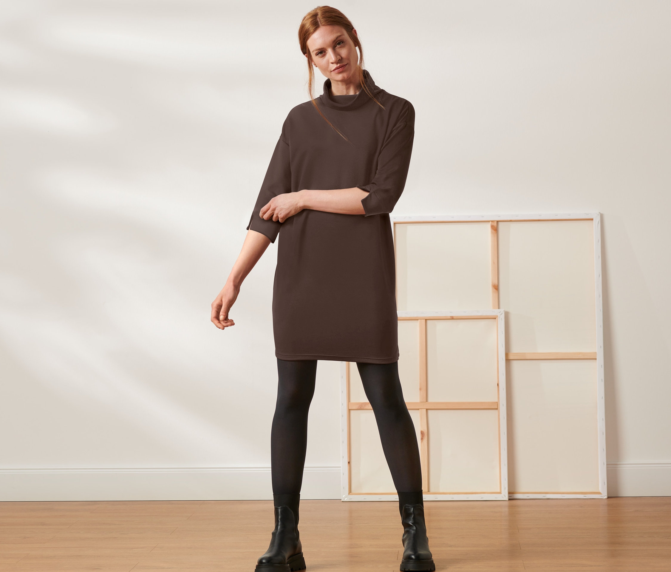 Frau posiert in einem braunen Sweatkleid.