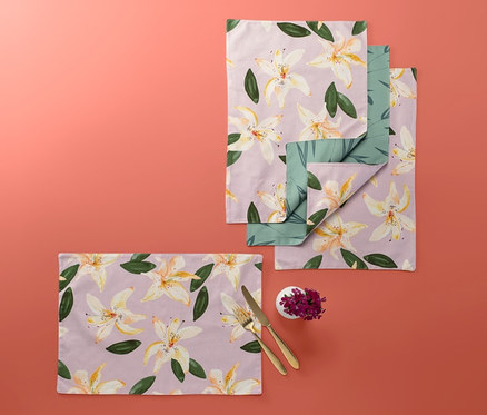 Vier Wende-Platzsets mit Blumenmuster auf korallefarbenem Hintergrund.