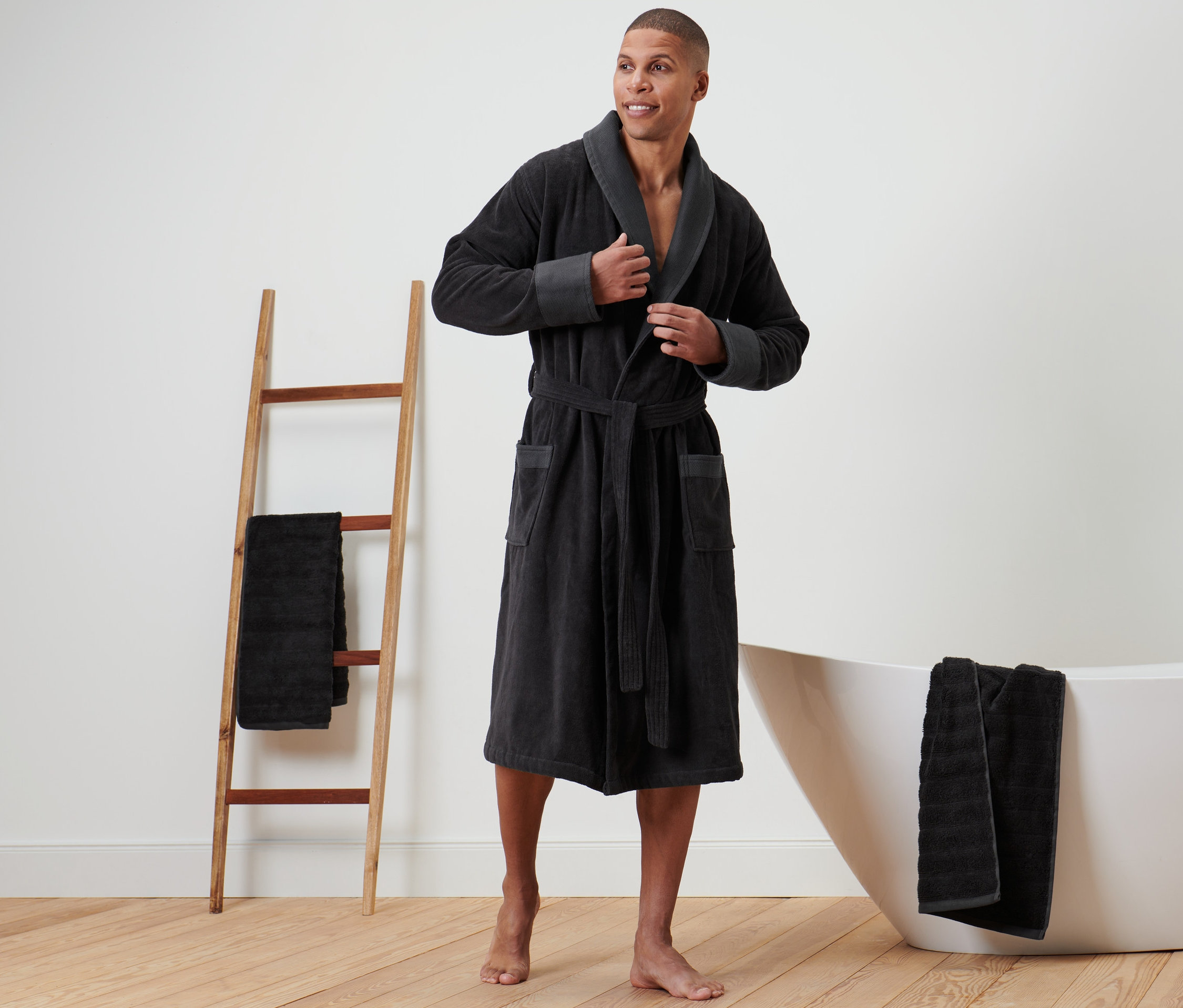 Mann steht im Badezimmer und trägt einen Herren-Veloursbademantel.