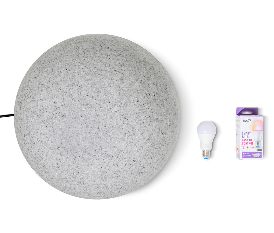 Eine Kugelleuchte mit smartem WiZ-LED-Leuchtmittel liegt neben einer Glühbirne und einer Glühbirnenverpackung.