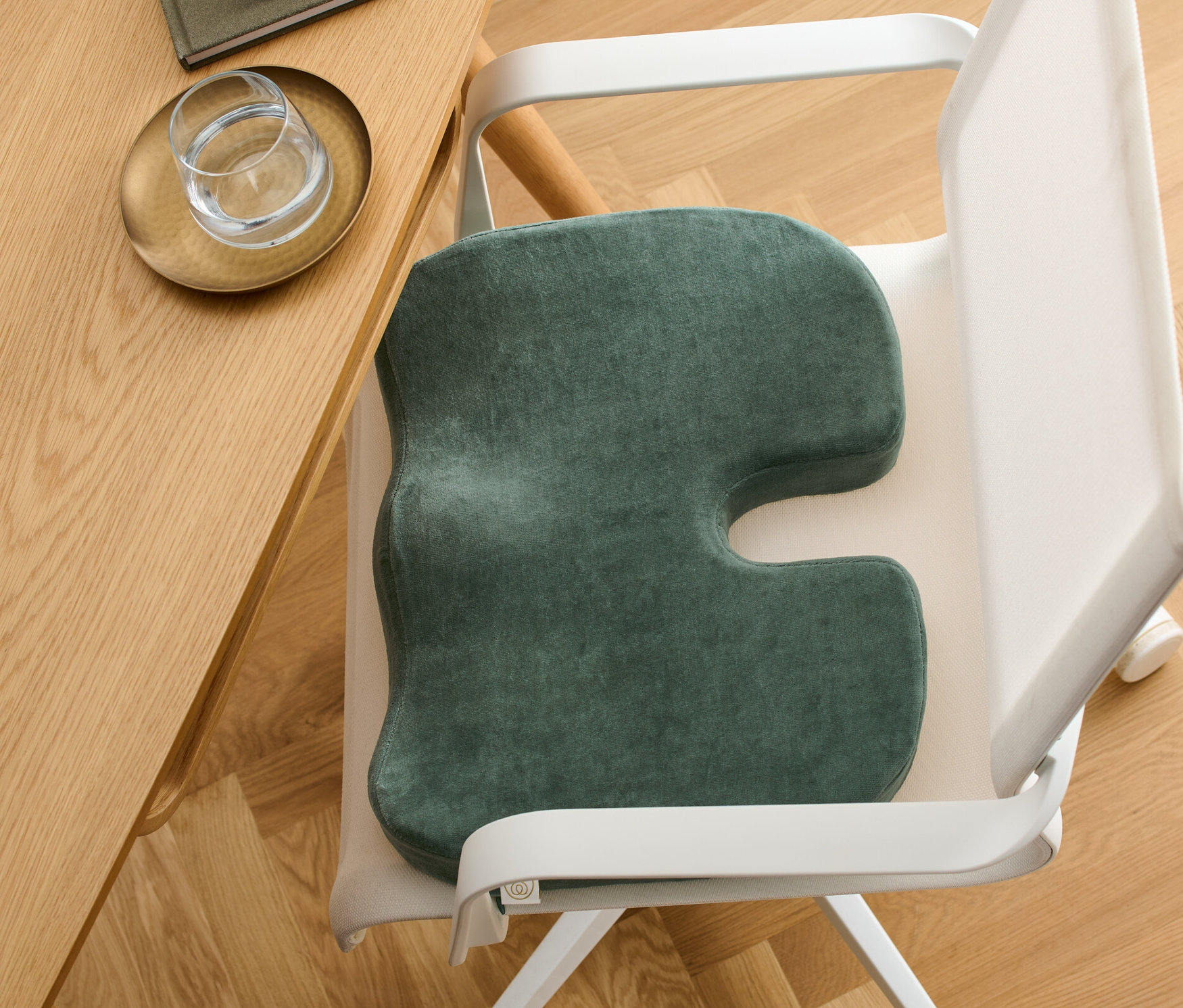 Ein Memory-Foam-Sitzkissen liegt auf einem weißen Bürostuhl neben einem Holztisch.