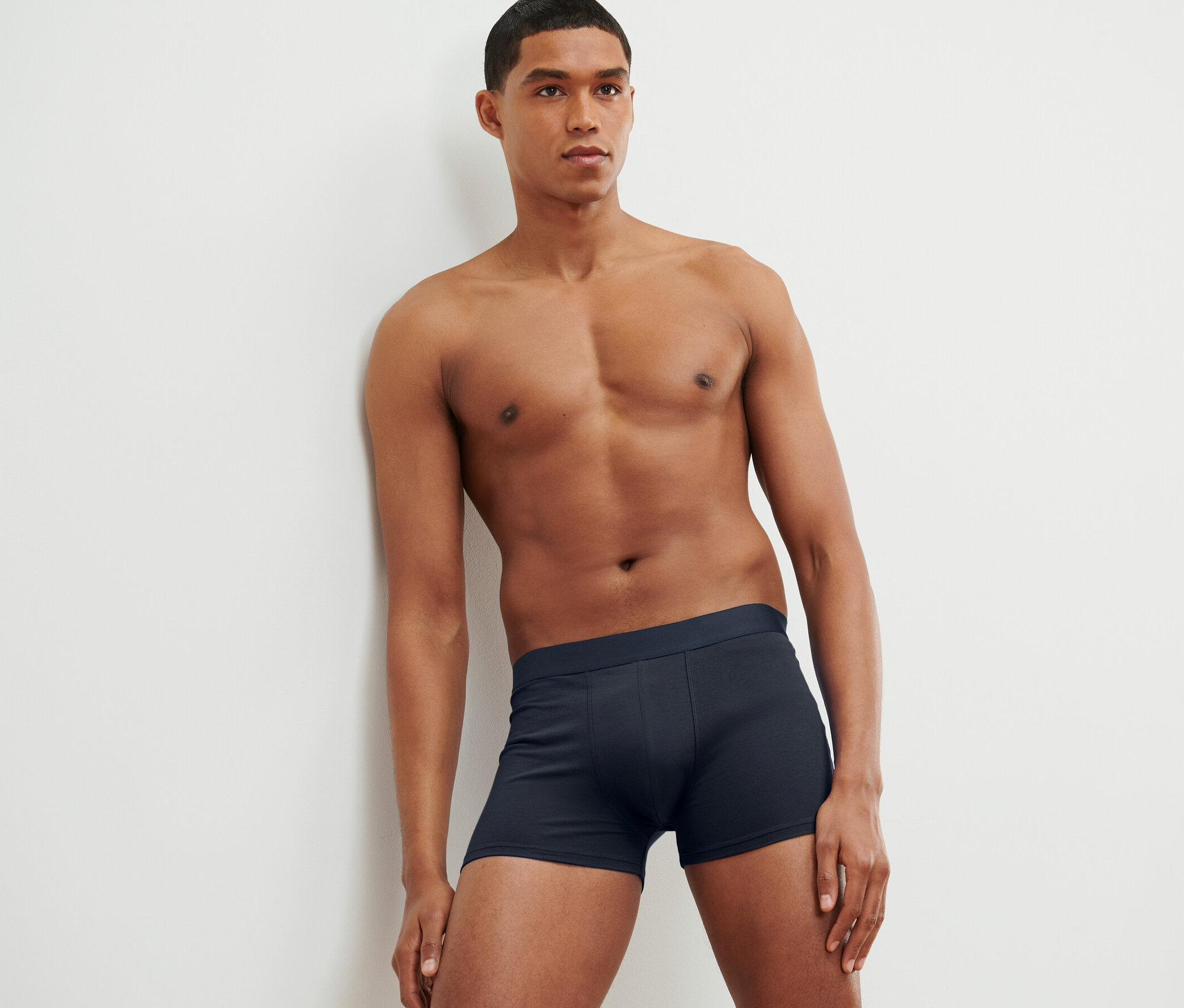 Mann lehnt an Wand und trägt 4 Slipboxer.