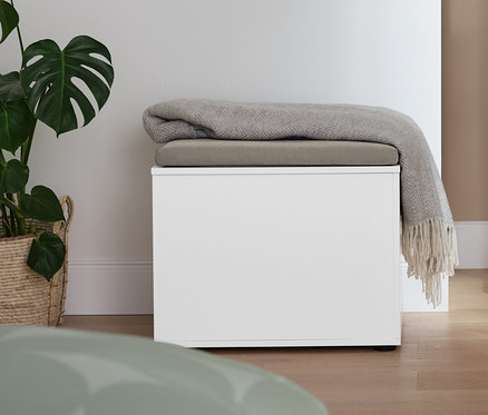 Im Raum stehen ein stummer Diener und eine Truhe mit Sitzmöglichkeit, auf der eine Decke liegt.
