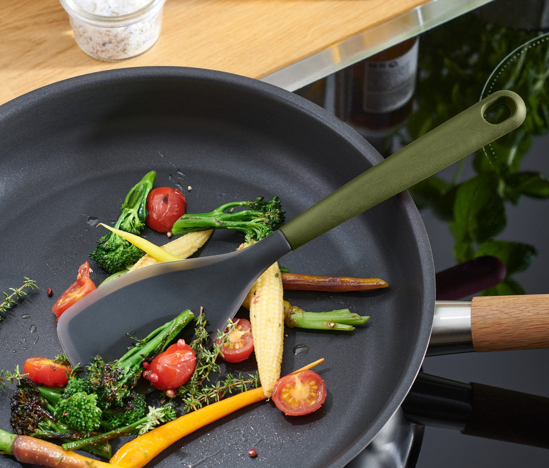 Multifunktions-Kochlöffel rührt Gemüse in einer Pfanne.