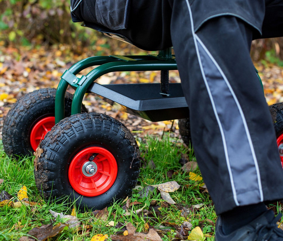 Mann sitzt auf Outdoor-Rollsitz »Deluxe« mit schwarzen Rädern mit roten Naben auf Gras, inklusive Schutzhülle.