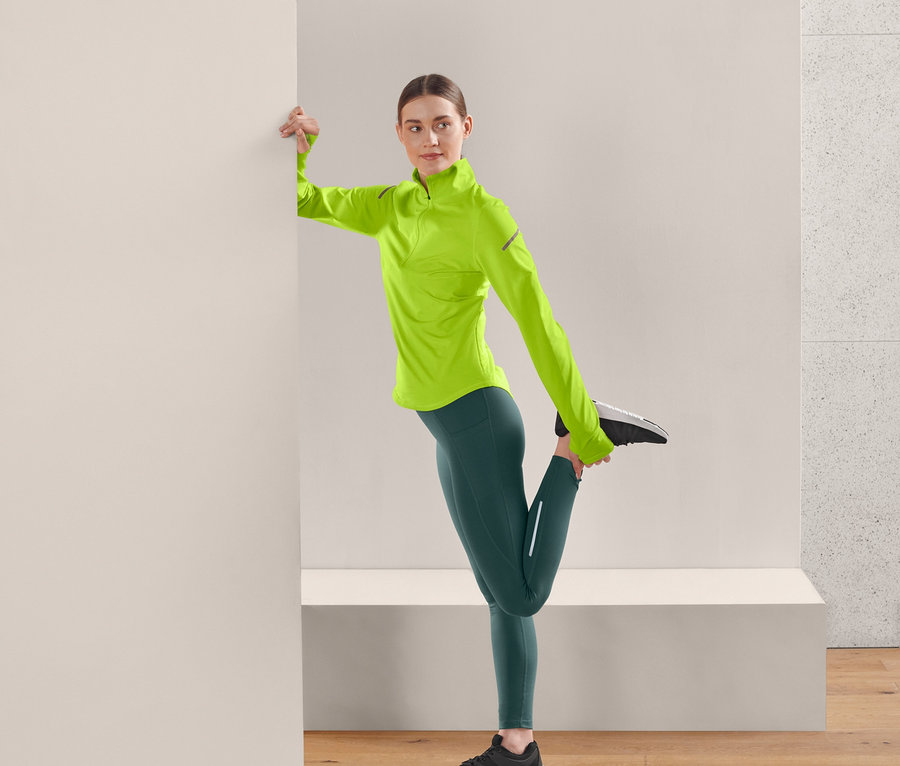 Frau dehnt Bein in dunkelgrüner Thermo-Lauftight.