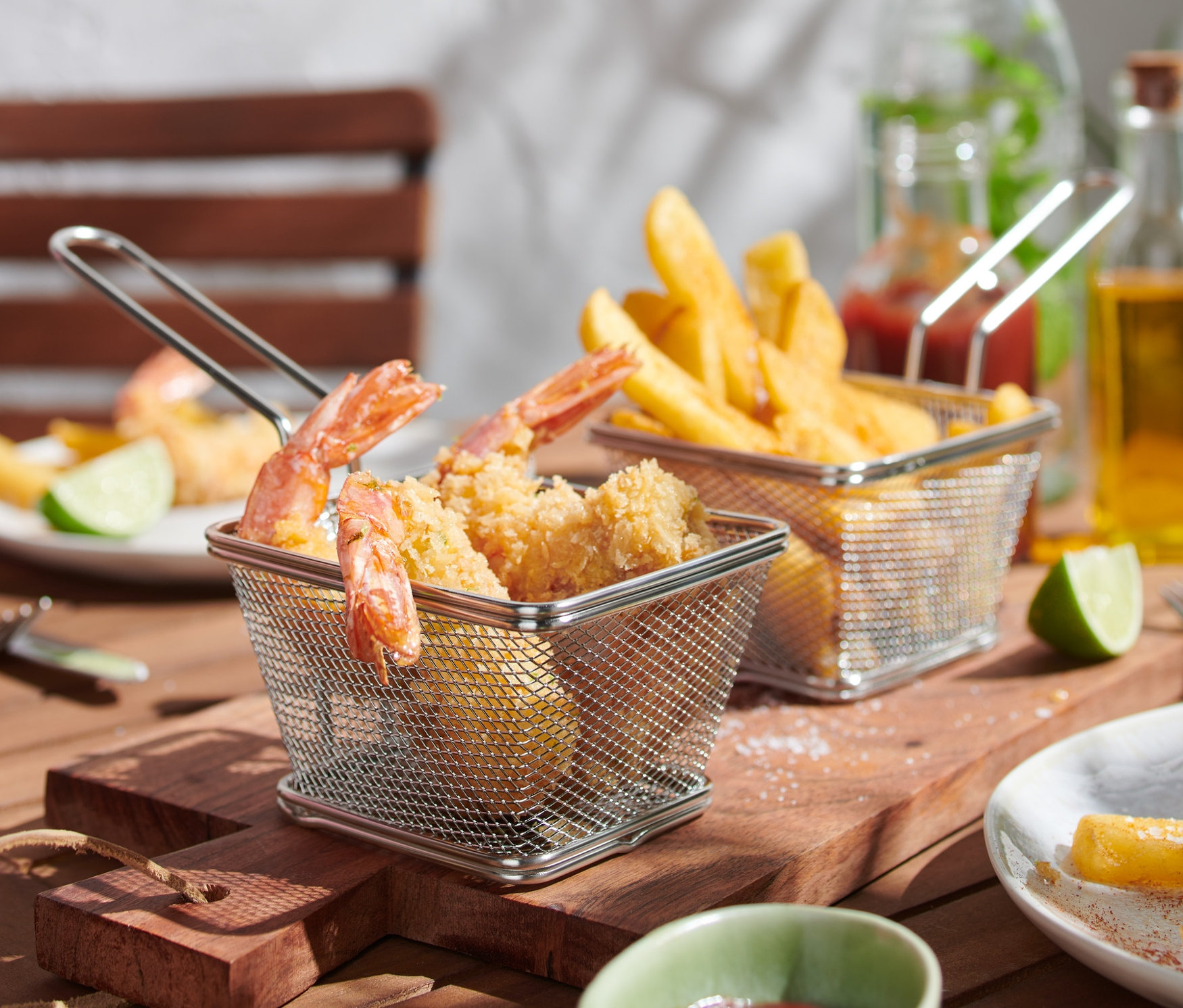 Zwei Servierkörbchen mit Essen auf einem Holztisch.