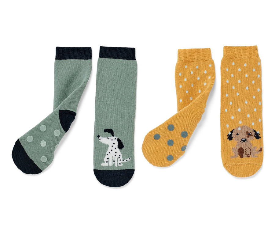 Zwei Paar Kinder-Antirutsch-Socken: ein Paar grün mit Dalmatiner-Motiv, ein Paar gelb mit Welpen-Motiv.