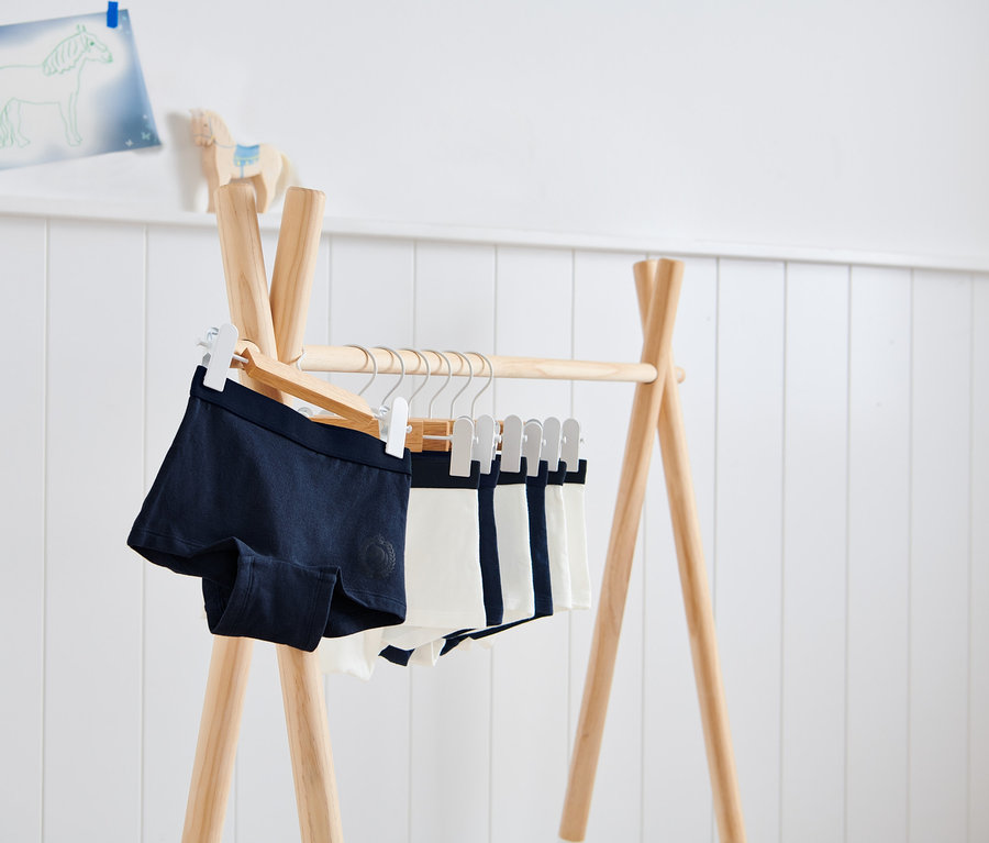 Auf einem Holzständer hängen 7 Kinder-Pantys.